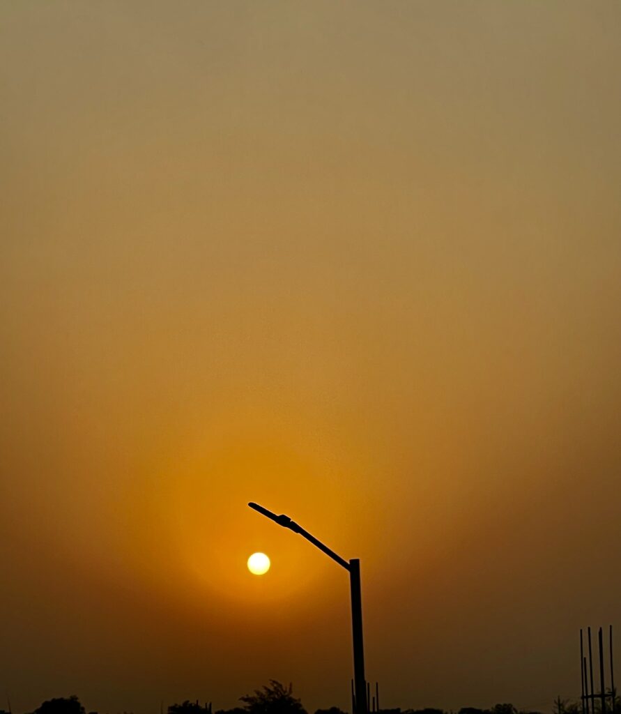 A mesmerizing sunset view with vibrant hues of orange and pink lighting up the sky, captured on the journey back from the Taj Mahal in Agra.